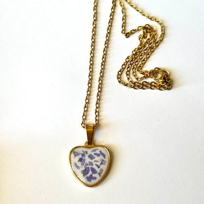 Bloomsake gold heart pendant necklace with preserved purple petals, chain laid flat on white background.