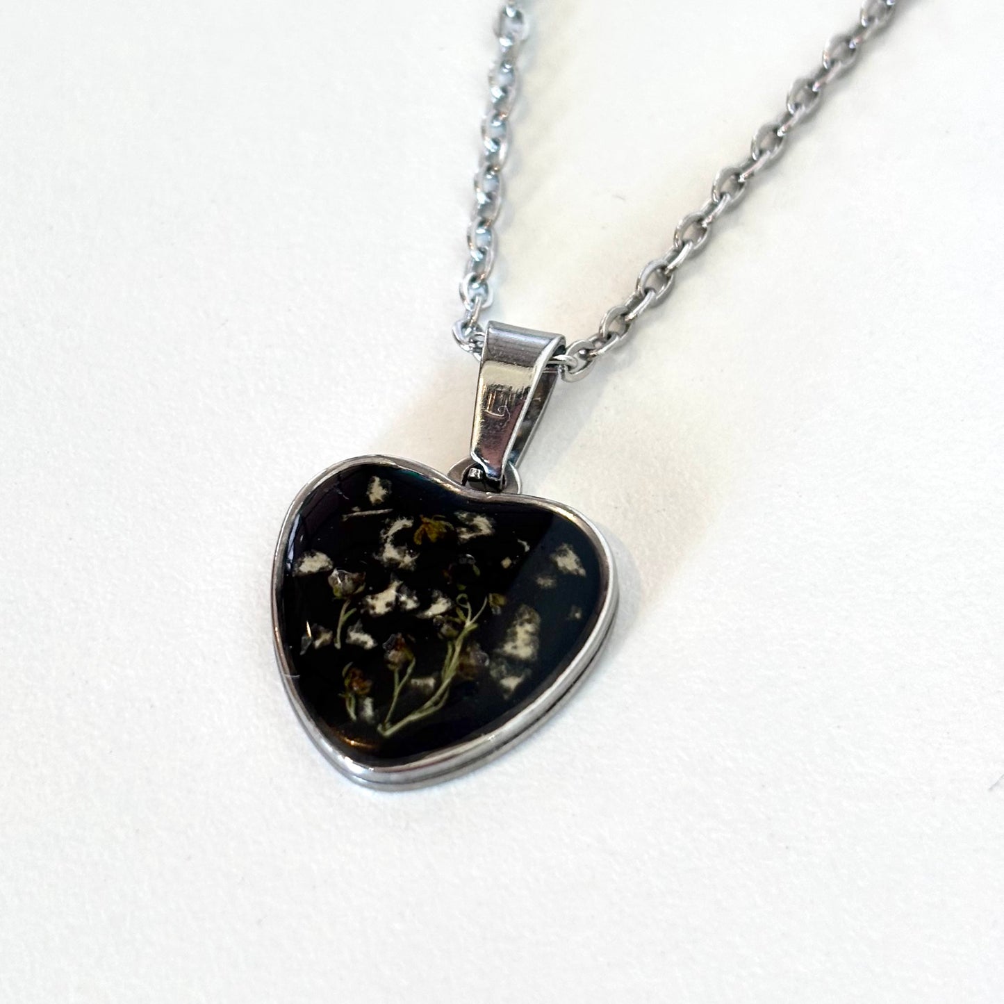 Bloomsake silver heart pendant necklace with preserved flowers in dark resin, full necklace hanging view.