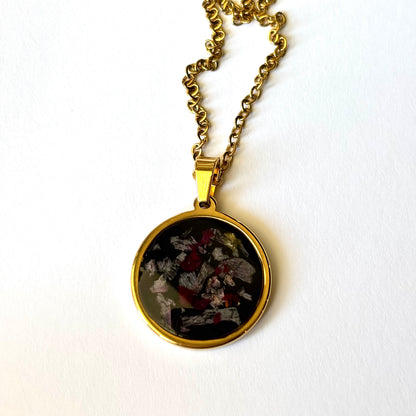 Bloomsake Margot Necklace with preserved flower petals in dark resin gold round pendant, angled view with gold chain.